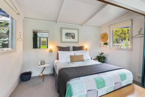 a bedroom with a bed and two windows at Apollo Bay Beach Bungalow - Couples Retreat in Apollo Bay