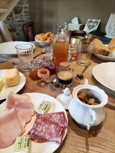 a wooden table topped with plates of food and drinks at Paddock Lodge - Suites Wellness & Chambres d'hôtes in Stoumont