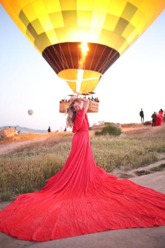 a woman in a red dress carrying a load on her head at Mak's Cave House in Uchisar