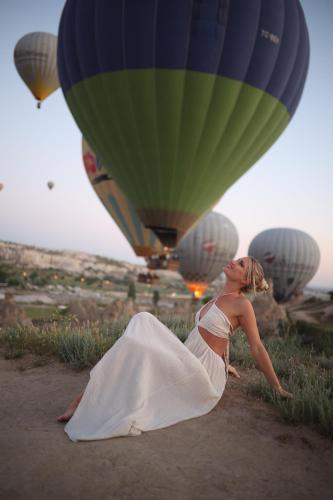a woman in a wedding dress laying on the ground with hot air balloons at Mak's Cave House in Uchisar