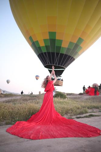 a woman in a red dress is holding a hot air balloon at Mak's Cave House in Uchisar
