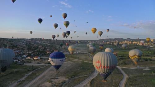 a bunch of hot air balloons flying over a city at Mak's Cave House in Uchisar