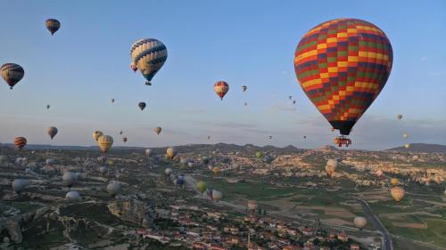 a bunch of hot air balloons flying over a city at Mak's Cave House in Uchisar