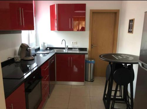 une cuisine avec des placards rouges et une petite table dans l'établissement Grand logement à 300 mètres de la gare, à Mantes-la-Jolie