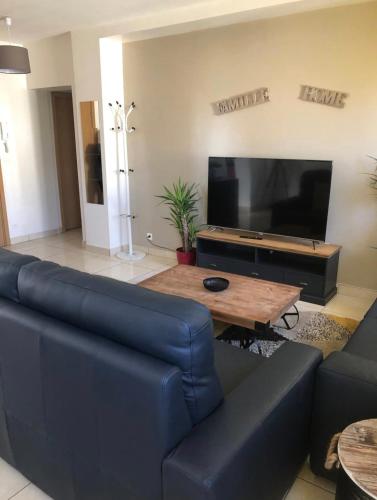 un salon avec un canapé bleu et une télévision à écran plat dans l'établissement Grand logement à 300 mètres de la gare, à Mantes-la-Jolie