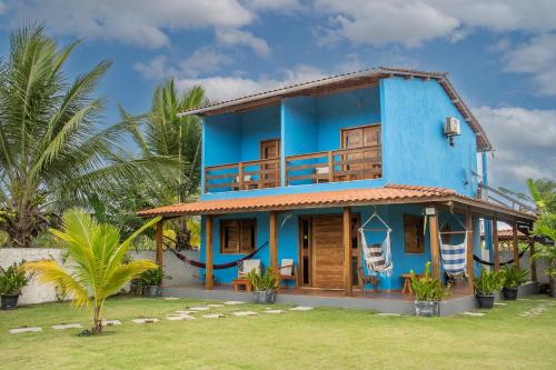 a blue house with a balcony and palm trees at Recanto Ancora Azul - Taipu de Fora in Barra Grande