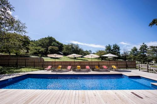a swimming pool with chairs and umbrellas at First Class Backpackers Inn DAISEN - FBI DAISEN in Daisen