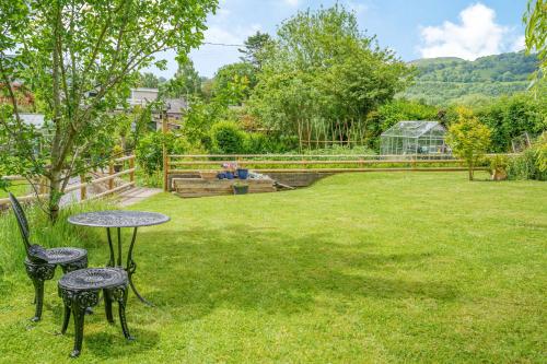a garden with two tables and chairs in the grass at Kavieng in Crickhowell