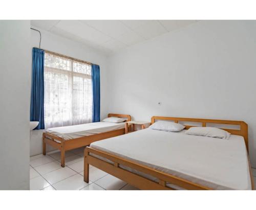 una habitación con dos camas y una ventana en Pall Inn Puncak Mitra RedDoorz, en Bogor