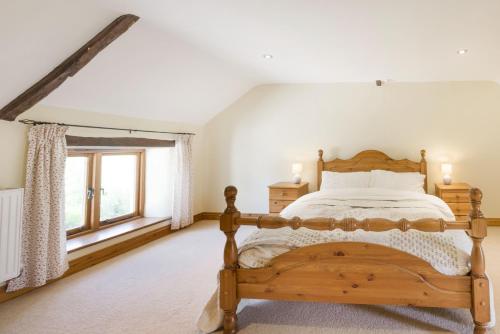 a bedroom with a wooden bed and a window at Groves Fishleigh in Hatherleigh