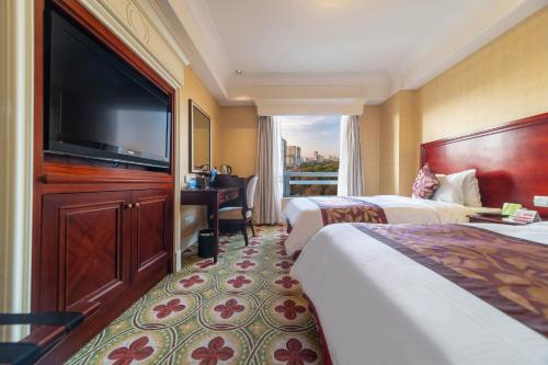 a hotel room with two beds and a flat screen tv at Ramada Yichang Hotel in Yichang