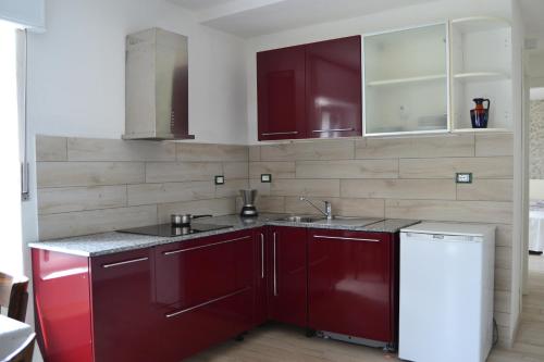 a kitchen with red cabinets and a white refrigerator at Casa Adriana con incantevole vista lago in Bee