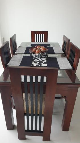 a wooden table with chairs and a plate of donuts on it at Rodrigo Apartments 3 in Boralesgamuwa