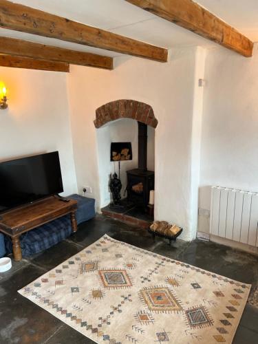 a living room with a television and a fireplace at The Cottage St Kew in Port Isaac