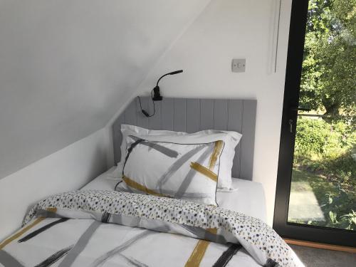 a bedroom with a bed with a pillow and a window at The Cartlodge in Hollesley