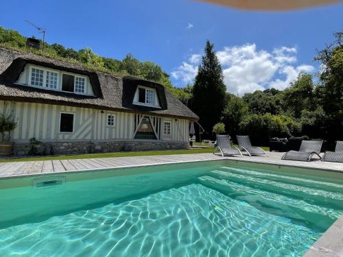 a swimming pool in front of a house at LES 2 CHAUMIÈRES Piscine & Spa in Ablon