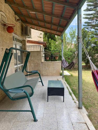 a hammock and a chair on a patio at דירת גן מרווחת במיקום מעולה עם נטפליקס חינמי in Ma'ale Adumim