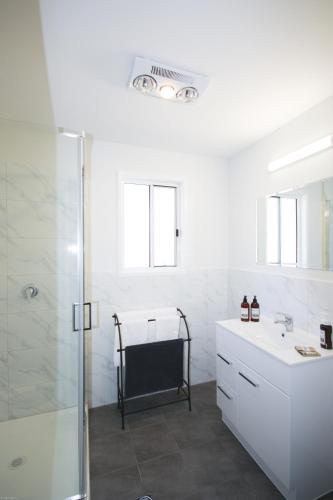 a white bathroom with a shower and a sink at Glen Lough Cabins in Glen Aplin