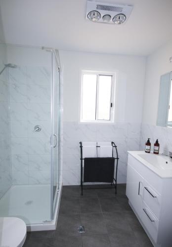 a white bathroom with a shower and a sink at Glen Lough Cabins in Glen Aplin