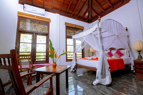 a bedroom with a canopy bed and a table at Niyagama House in Galle