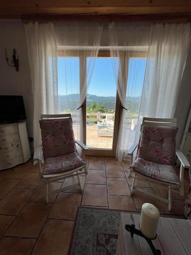 a living room with two chairs and a large window at Dom pod kogutem in Laliki