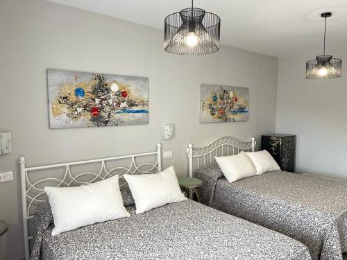 a bedroom with two beds and two paintings on the wall at Coccoa Boutique Hotel in Boó de Piélagos