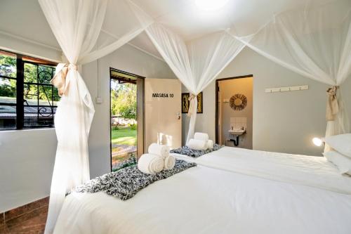 Shoestrings Backpackers Lodge Vic Falls في شلالات فيكتوريا: غرفة نوم بسرير كبير وستائر بيضاء