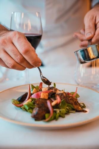 a person eating a plate of food with a glass of wine at Novotel Toulouse Centre Wilson in Toulouse