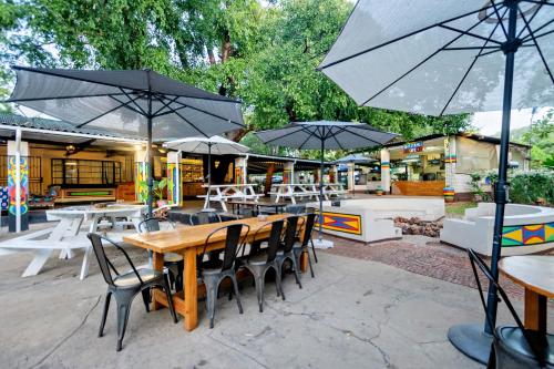 an outdoor patio with tables and chairs and umbrellas at Shoestrings Backpackers Lodge Vic Falls in Victoria Falls