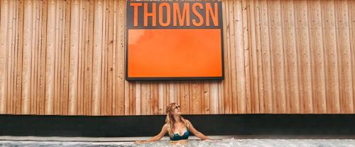 a woman in a bikini sitting in front of a building at THOMSN-Alpine Rock Hotel in Saalbach-Hinterglemm