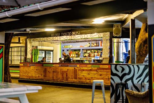 a restaurant with a bar with people sitting at it at Shoestrings Backpackers Lodge Vic Falls in Victoria Falls