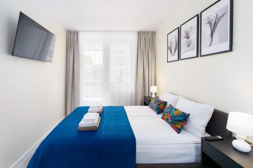 a bedroom with a large bed with a blue blanket at Apartamenty Adyl Platany in Kołobrzeg