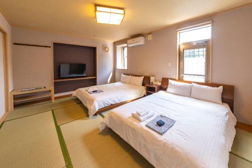 a hotel room with two beds and a tv at ETAVIA Yufuin Kinrinko in Yufuin