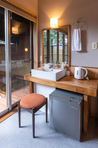 a bathroom with a sink and a counter with a stool at ETAVIA Yufuin Kinrinko in Yufuin