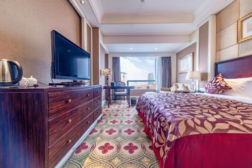 a hotel room with a large bed and a flat screen tv at Ramada Yichang Hotel in Yichang