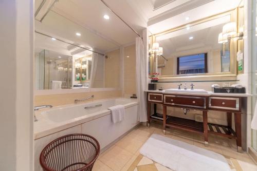 a bathroom with a tub and a sink and a mirror at Ramada Yichang Hotel in Yichang