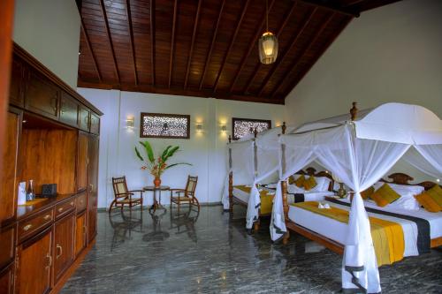 a bedroom with two beds and a table and chairs at Niyagama House in Galle