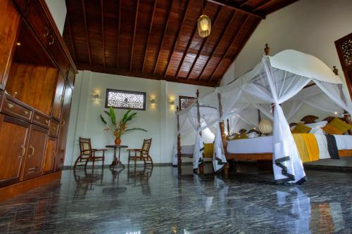 a bedroom with two beds and a table and chairs at Niyagama House in Galle