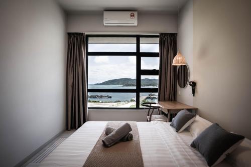 a bedroom with a bed and a large window at Jesselton Quay by Pinstay in Kota Kinabalu