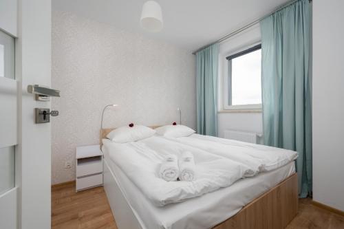 a bedroom with a white bed with two masks at Apartment Kamienna Krzyki with FREE GARAGE Wrocław by Renters in Wrocław
