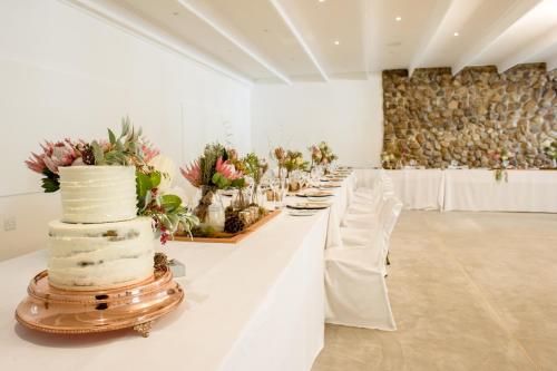 a long white table with a wedding cake on it at Mont d'Or Swartberg Hotel in Prince Albert