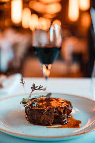 a plate with a piece of meat and a glass of wine at Novotel Toulouse Centre Wilson in Toulouse