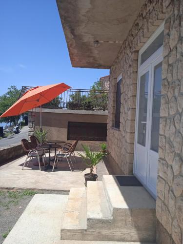 a patio with a table and an umbrella and chairs at Apartment Luka in Senj