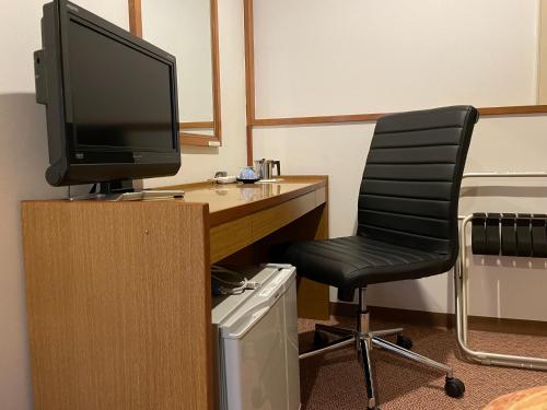 a desk with a computer monitor and a chair at Hotel Shibataya in Kurihara