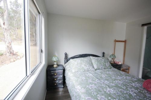 a bedroom with a bed and a window at Glen Lough Cabins in Glen Aplin
