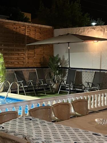 uma piscina com cadeiras, uma mesa e um guarda-sol em casa grande en Córdoba, pueblo de la Victoria , 6 dormitorios em La Victoria