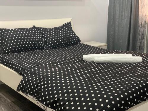 a black and white bed with polka dot sheets at Apartament B Orizont in Bacău