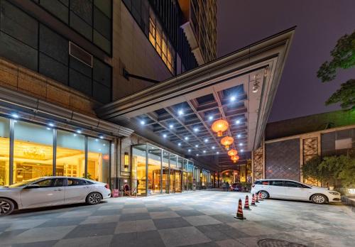 two cars parked in front of a building at night at Ramada Yichang Hotel in Yichang