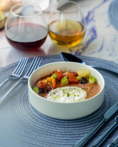 a bowl of soup on a plate with two glasses of wine at OBLU XPERIENCE Ailafushi - All Inclusive with Free Transfers in Male City