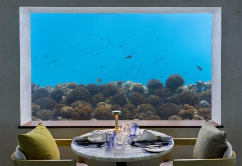 a table in front of a large window with an aquarium at OBLU XPERIENCE Ailafushi - All Inclusive with Free Transfers in Male City